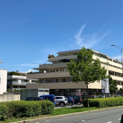 Modern társasház erkélyekkel és parkoló autókkal városi környezetben